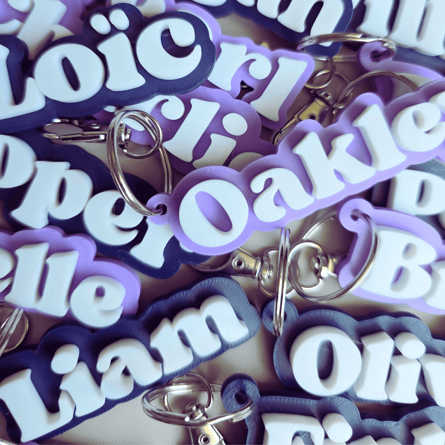 Collection of personalized keychains with names in purple and white letters.
