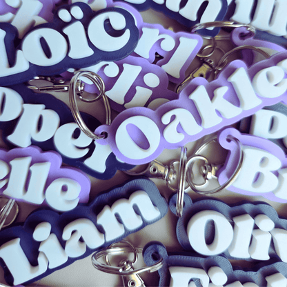Collection of personalized keychains with names in purple and white letters.