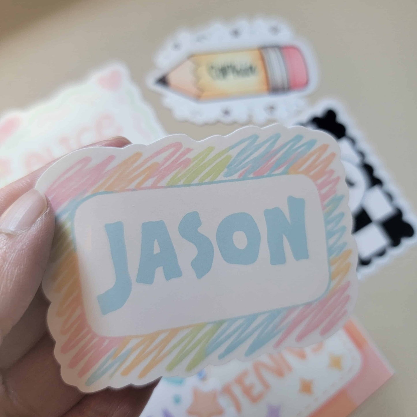 Colorful sticker with 'JASON' text held by a hand on a light background