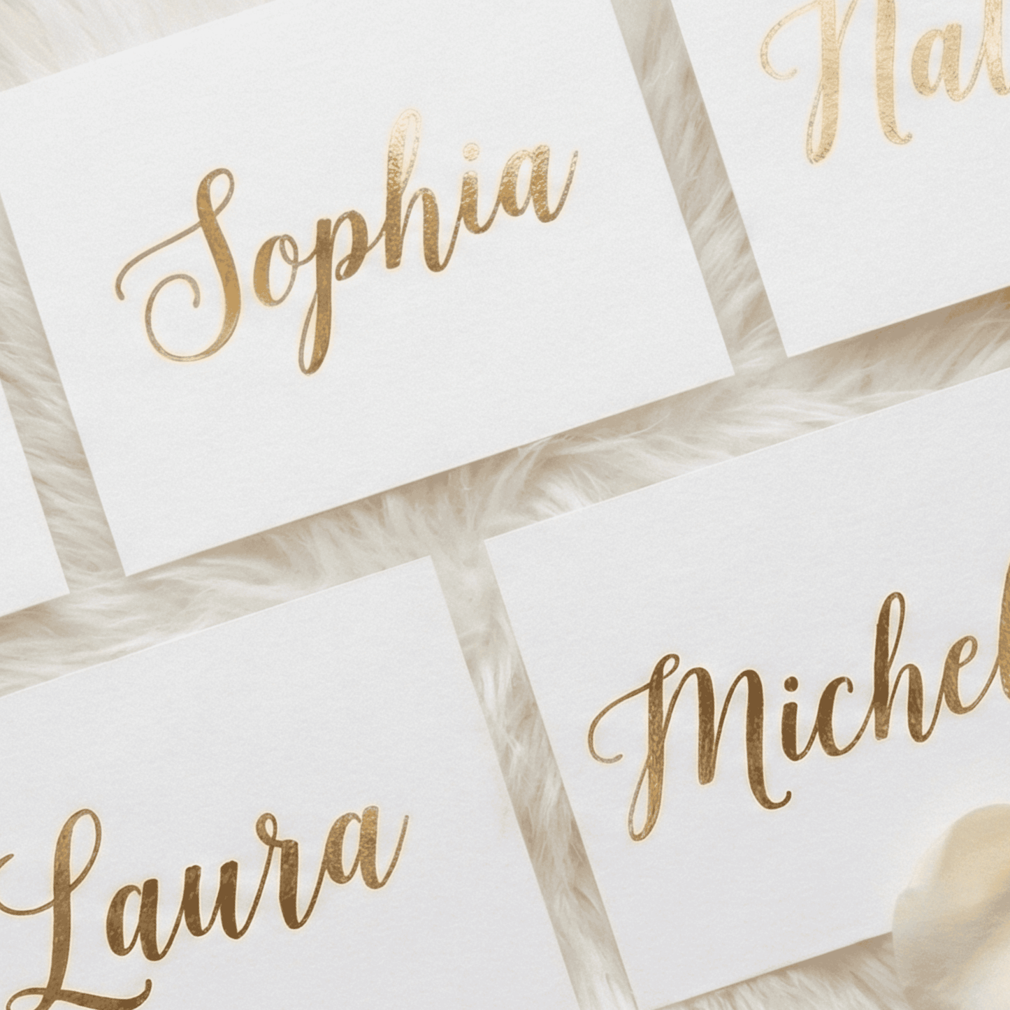 Gold-foil names on white cards with a soft focus background