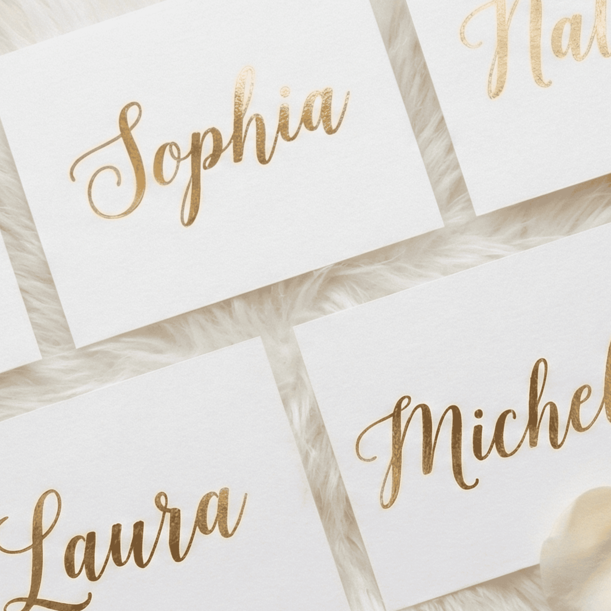 Gold-foil names on white cards with a soft focus background