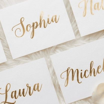 Gold-foil names on white cards with a soft focus background