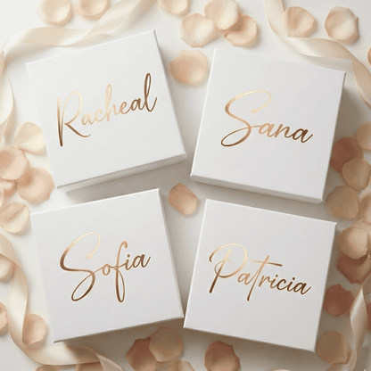 Four white boxes with gold names on a decorative background with petals and ribbons.