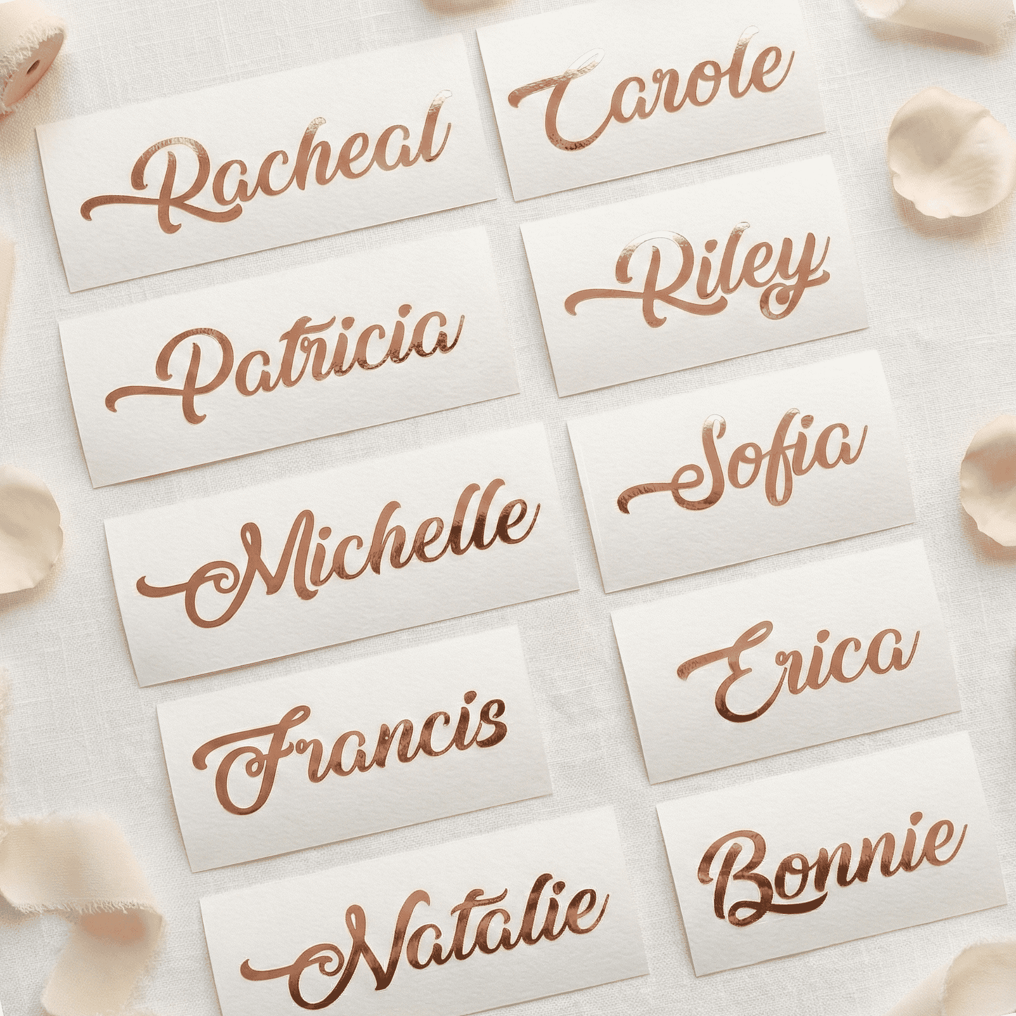 Name cards with copper names on a light background with petals